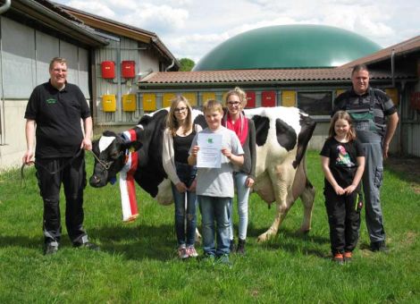 Bei der jüngsten Milchleistungsprüfung erreichte im Betrieb der Familie Norbert Hild in Gedern die Bruce Tochter DE 06 62189470, Stallnummer 87, 100 000 kg Lebensleistung. Die am 23. Juli 2003 geborene, Deutsche Holsteins Schwarzbunte, kalbte zum ersten Mal am 21. Oktober 2005 und schloss mit einer Erstlaktationsleistung von 7 786 kg mit 4,30 Prozent Fett, 3,62 Prozent Eiweiß diese ab. Die Höchstleistung erreichte die Kuh mit der vierten Laktation mit 13 308 kg Milch und 416 Fett kg sowie 439 Eiweiß kg. Beim letzten Jahresabschluss wurden 10 836 kg Jahresleistung mit 3,89 Prozent Fett und 3,16 Prozent Eiweiß erreicht. Von den sechs weiblichen Nachkommen sind noch drei Kühe im Betrieb. Die Erstgeborene hat aktuell auch schon 70 015 kg Gesamtleistung in dem Betrieb erreicht. Nr. 87 ist eine sehr vitale und aktive Kuh, welches sie bei dem Fototermin zeigte. Das Umlegen der Ehrenschleife erforderte einige Anstrengung. Sie zeigte sich hier als „Chefin“ in der Herde. Die Züchterfamilie Hild GbR konnte im letzten Jahresabschluss 2014 mit 232 Kühen eine Durchschnittsleistung von 10 496 kg Milch mit 3,41 Prozent Fett und 3,33 Prozent Eiweiß aufzeigen. Aus dem Betrieb sind schon viele Nachzuchten über die Zuchtorganisation vermarktet worden. Die hessischen Rinderzüchter gratulieren der Familie Hild zu diesem Erfolg, in dem Club der 100 000 zu sein. Das Bild zeigt den Betriebsleiternachwuchs mit der Jubilarin.      Text/Foto: Achim Lohrey, LLH Wächtersbach